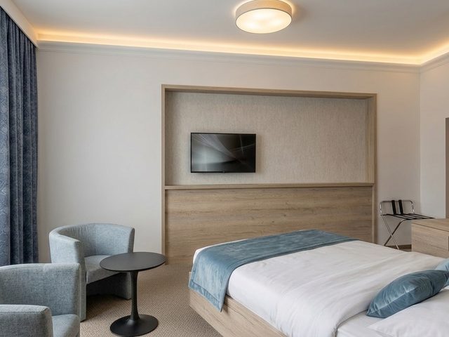 Hotel Borovany – pokoj s modrými doplňky a vestavěnou nikou s televizí